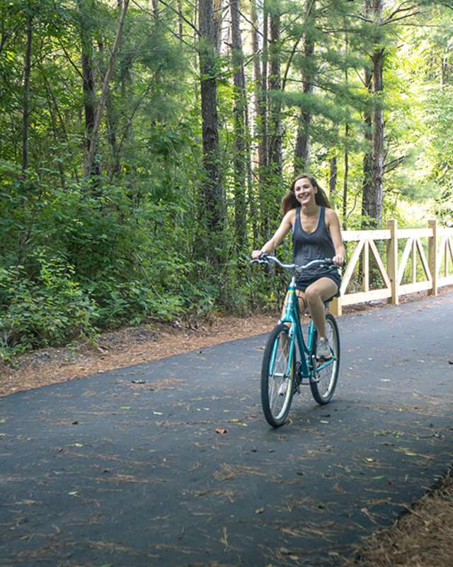 Two women right their bicycles along a forested section of the Thermal Belt Rail Trail in Rutherford County, NC.