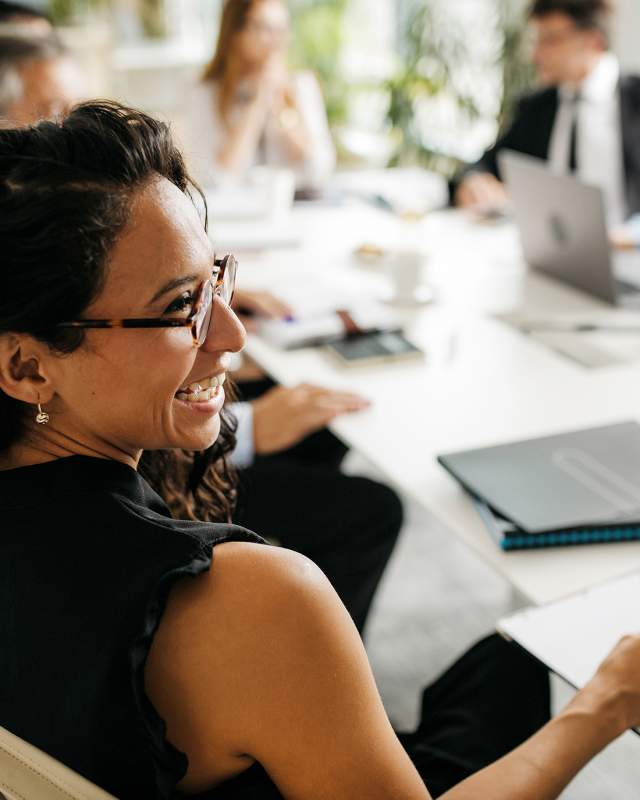 A woman glancing to her right and smiling during a meeting.