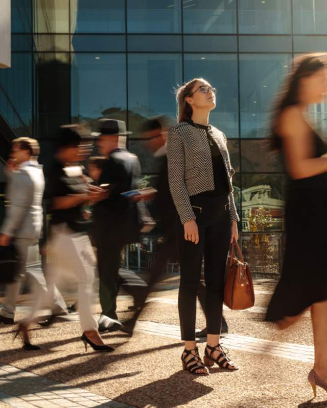 Woman standing while people walk past
