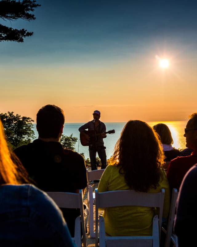 A crowd watches a concert as the sun sets