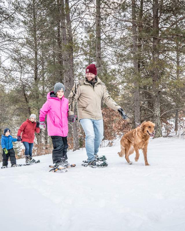 family and dog on a snowshoe trail