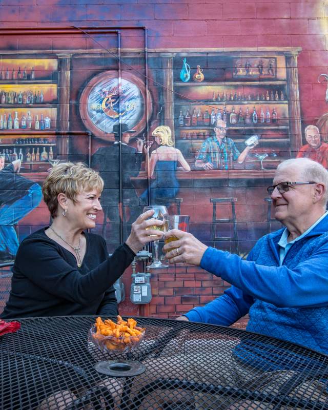 couple toasting in front of mural