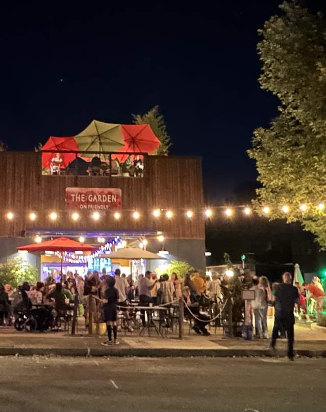 Garden on Friendly is lit up with lights and crowded with people around its outdoor patio.