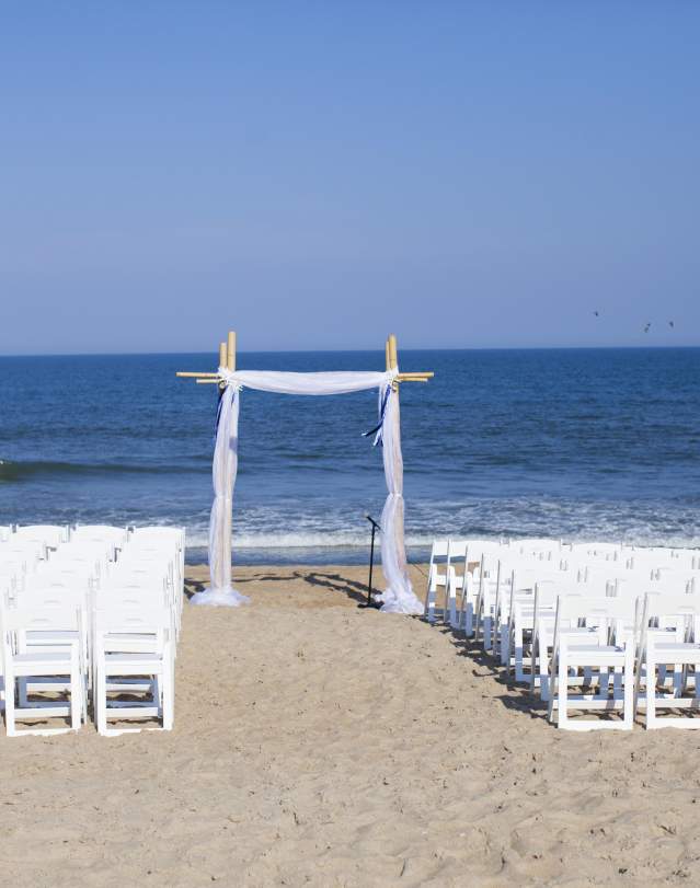 Chairs and an arbor set up for a wedding ceremony on the beach in the Outer Banks