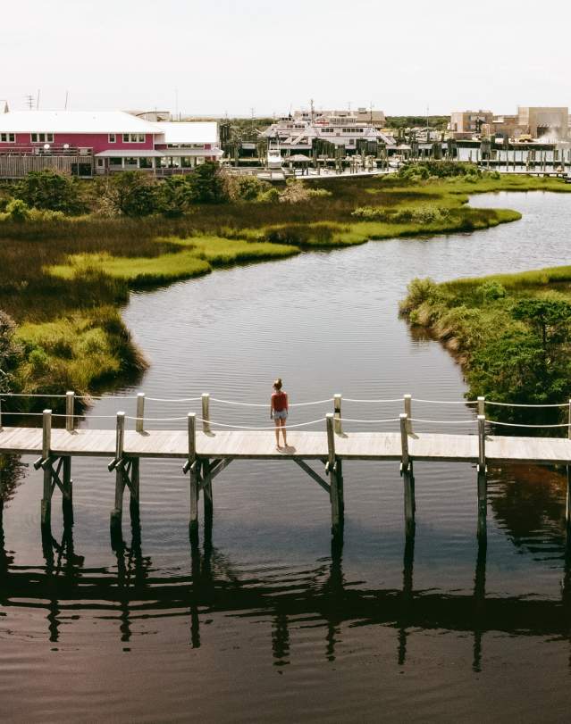 A woman walks across a wooden walkway at Hatteras Landing Marina.