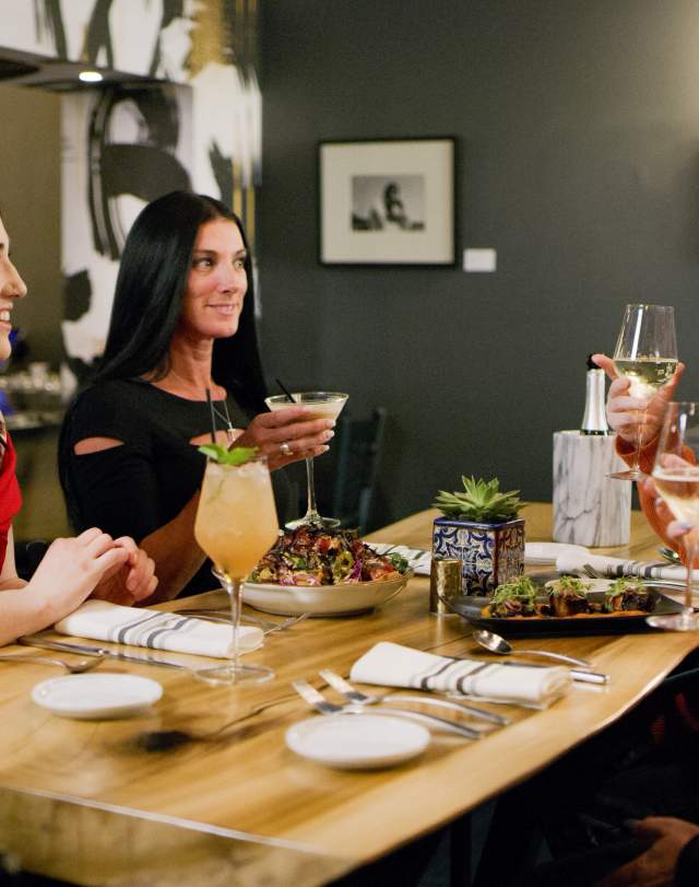 4 women sit at a restaurant table dining on gourmet food