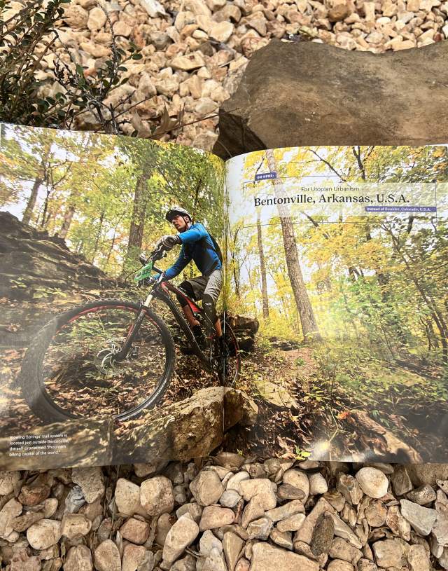 Open book on a rocky surface showing a mountain biker on a trail in Bentonville, Arkansas.