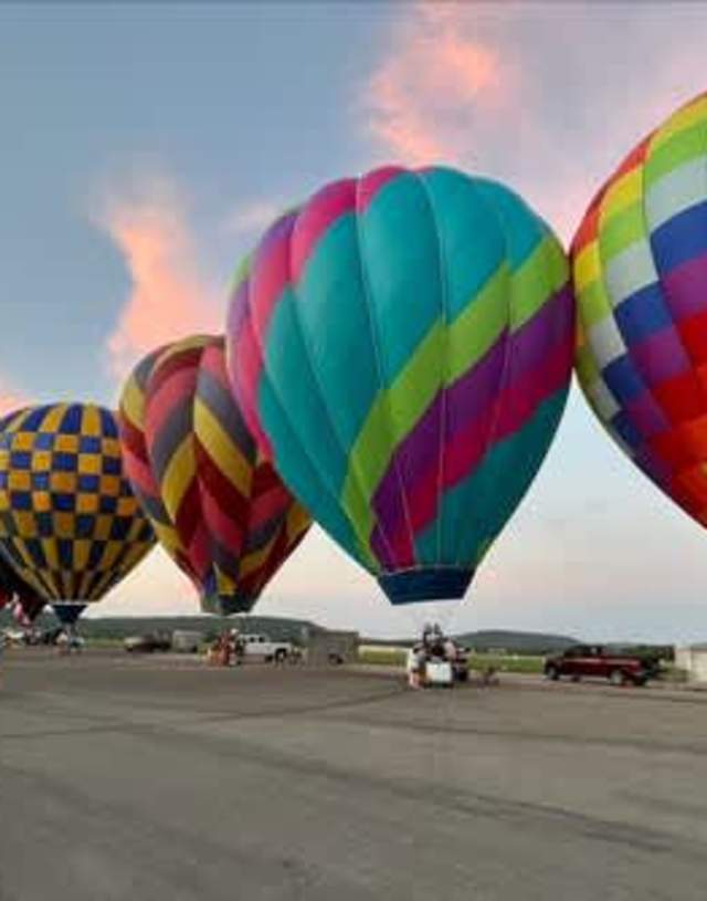 Hot air balloons in a line against a sunset