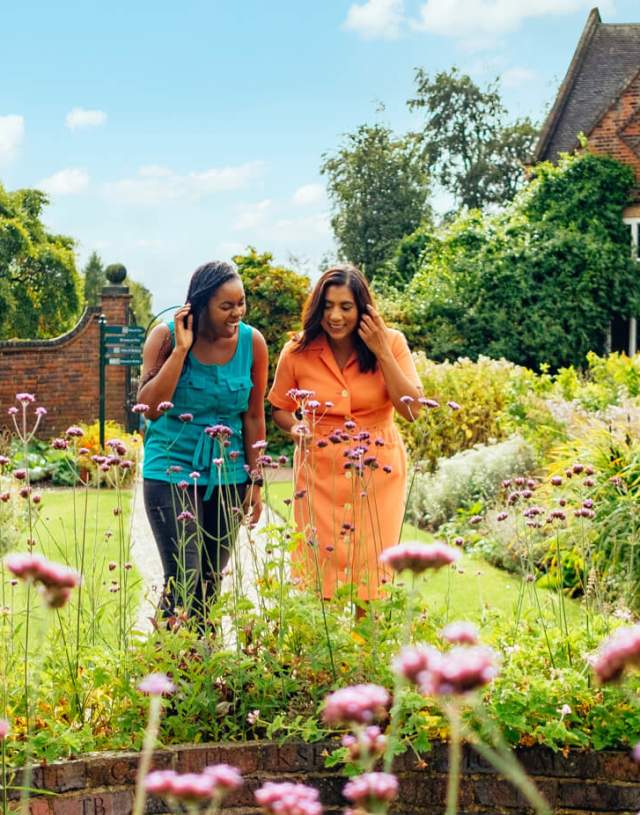 Two ladies looking at spring flowers in front of Winterbourne House and Garden