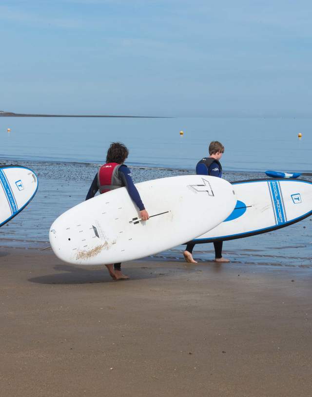 Four surfers enter the sea at Colwyn Bay