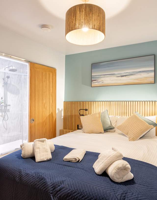 A cosy bedroom featuring a bed with a blue blanket and a wooden headboard, creating a warm and inviting atmosphere.