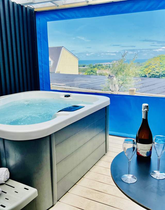 A hot tub situated on a deck with a bottle of wine nearby, suggesting a serene and luxurious retreat.