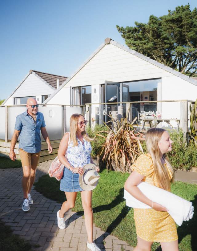 family outside lodge in Holiday Park in summer walking