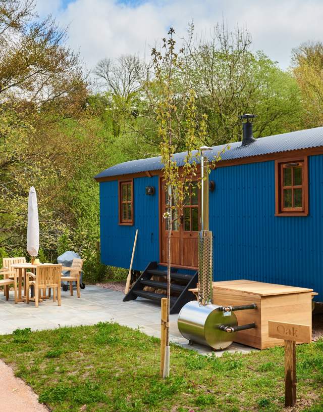 the outside of Shepherds hut painted in blue with garden furniture