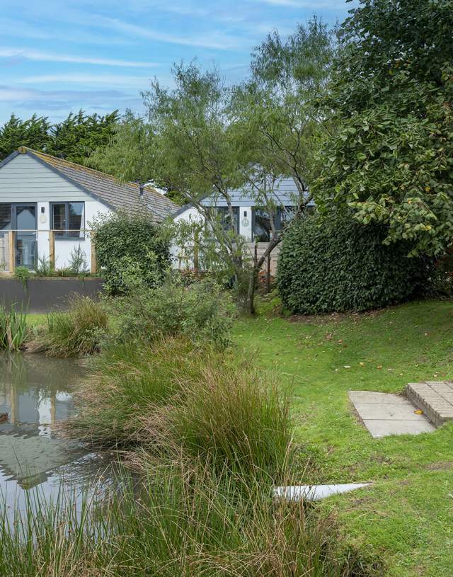 view of a pond and steps in the foreground, lodges behind on a summer day