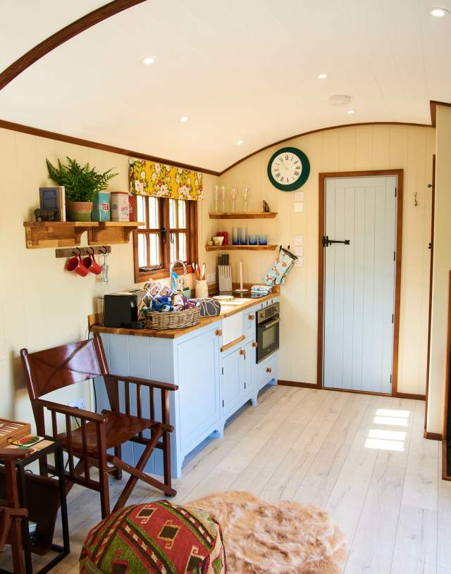inside of Shepherd's hut with kitchenette and log burner
