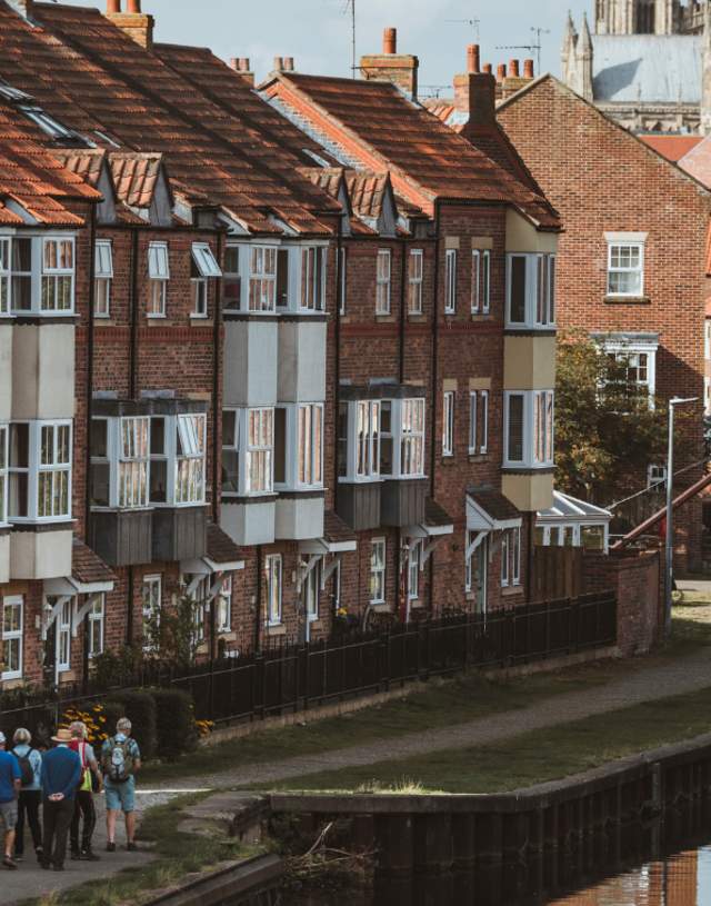 A view looking down Beverley beck with a walking group following the waters edge. Beverley Minster in the background.