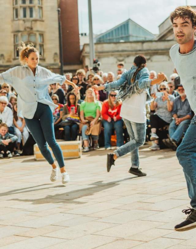 Freedom festival dancers perform in the sunshine in Queen Victoria Square with a crown surrounding them.