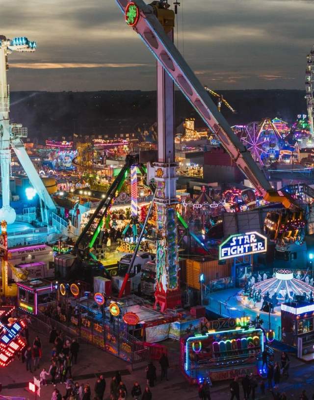 A panoramic view of Hull Fair at dusk with bright neon lights.