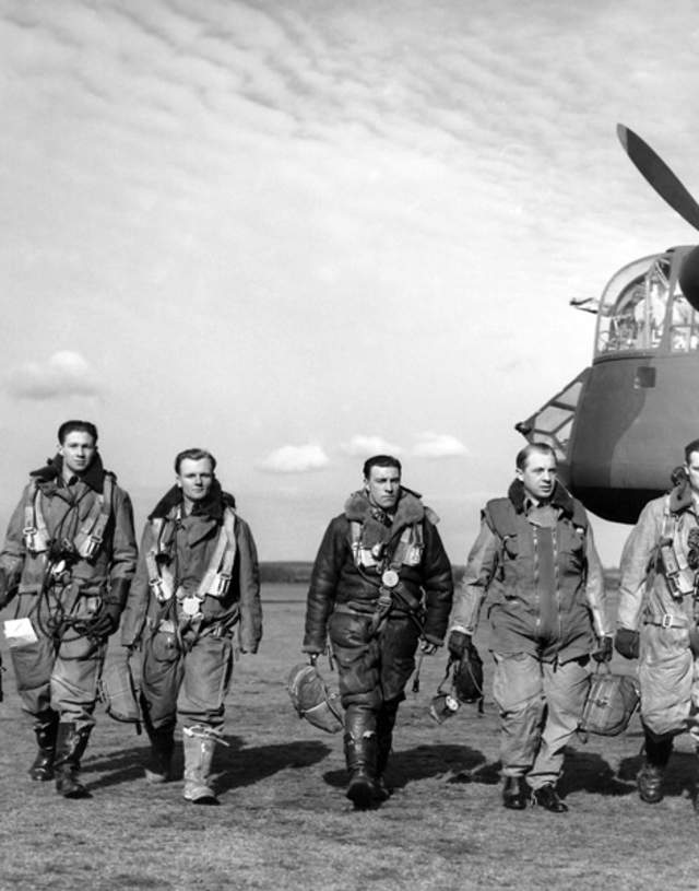 a line of pilots walking from a Lancaster bomber black and white