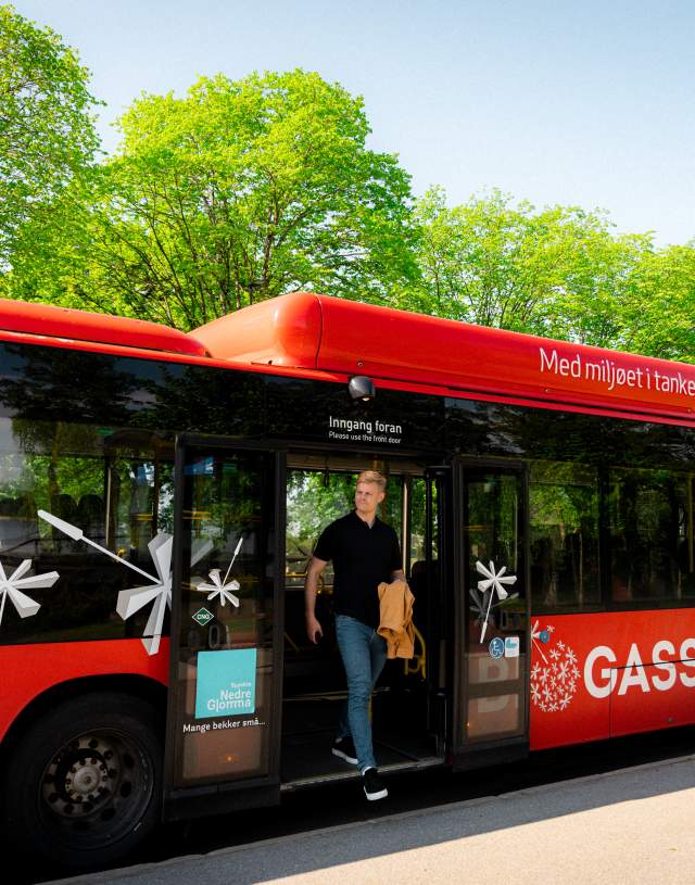Ung mann går av en rød Østfold-buss