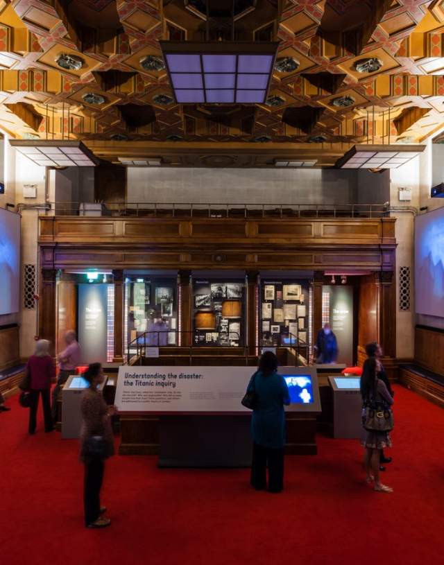 Inside the Titanic Exhibition at Seacity museum with people looking at information boards and screens on either side of the room