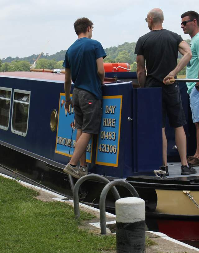 Farncombe Boat House - people standing on a narrowboat on a lock