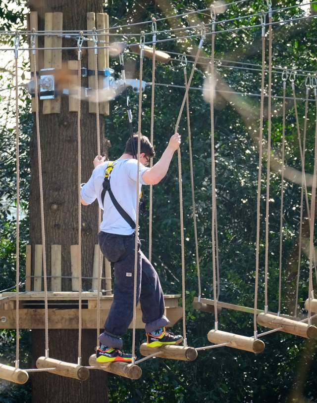 A man climbing across a rope bridge at Skywalk Adventures