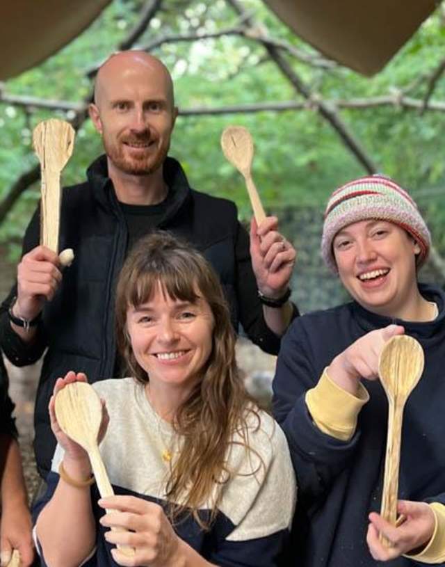 Men and women holding wooden spoons at Joy Farm