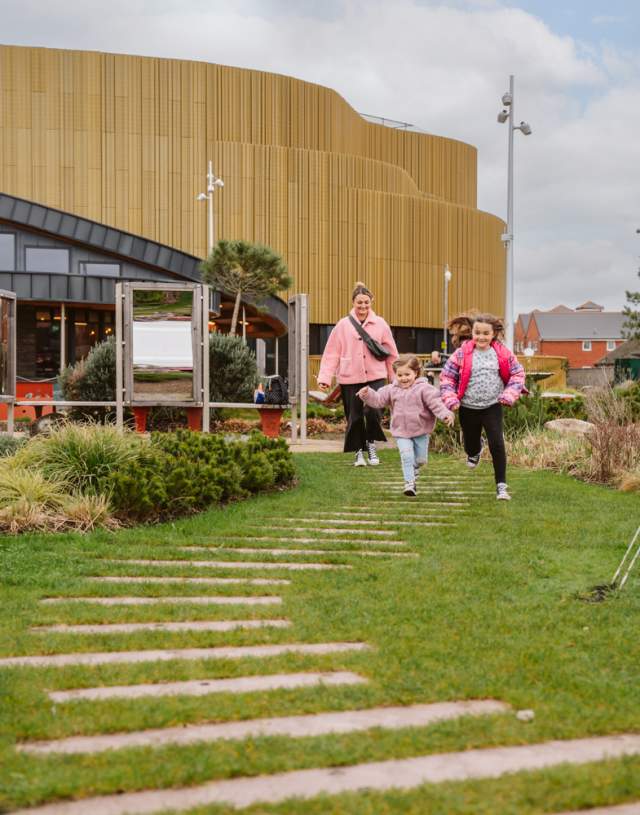 mum with children running excitedly into a park