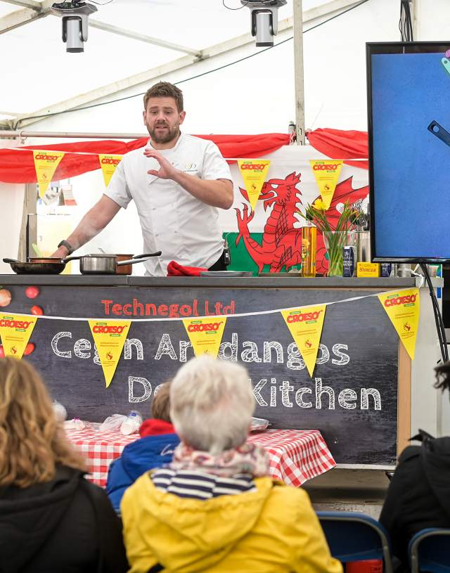 chef doing a live cooking demonstration to a crowd of people