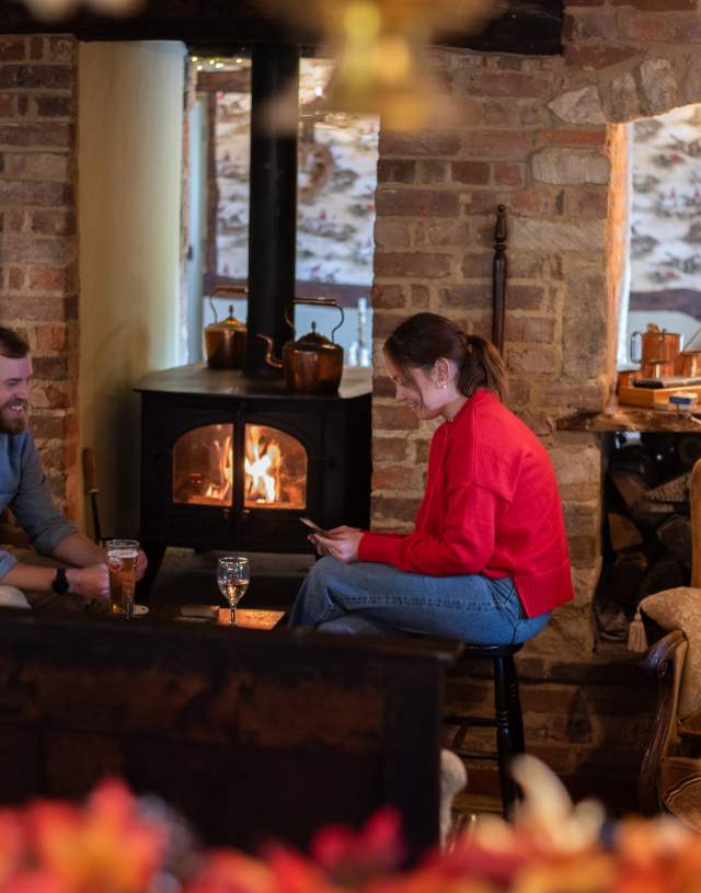 two people sat playing cards by a fire in a country pub
