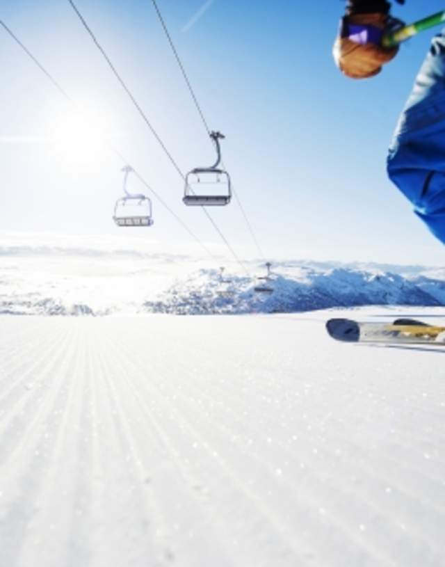 Skiier on newly prepared alpine slope and view of Hovden. Photo