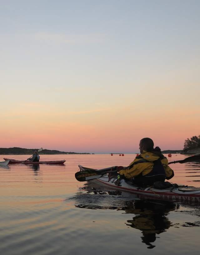 Three kayaks at sea by sunset