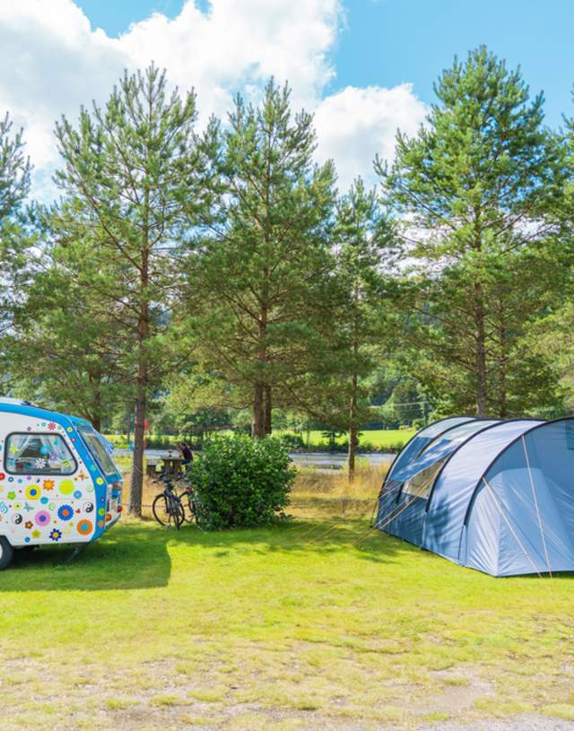 Bilde av telt og liten campingvogn ute i naturen