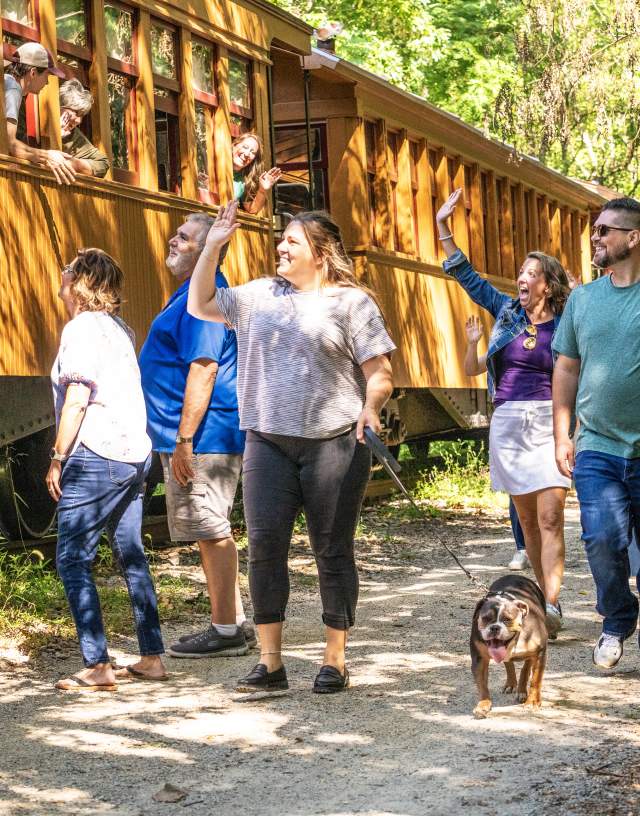 People enjoying a beautiful day walking alongside the steam engine on the heritage rail trail