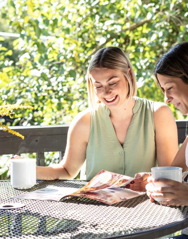 two women sitting at a table drinking coffee and planning their day using our York County Travel Guide