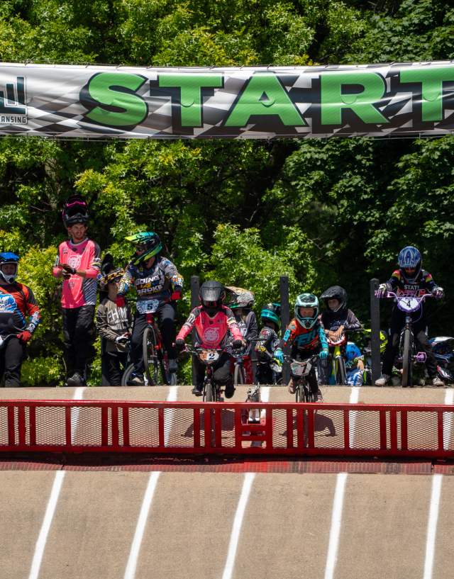 A group of BMX athletes lining up at the start, preparing for their run during the BMX State Race.