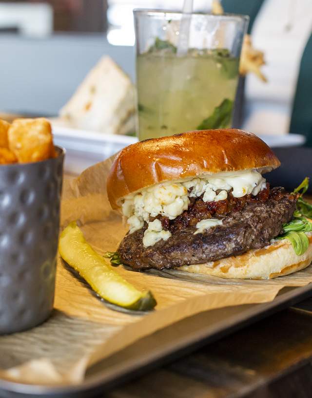 Black ad Bleu burger with a pickle spear and cajun tator tots