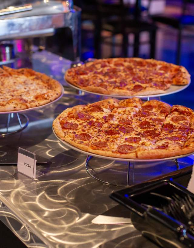 Three pizzas on a table with a label