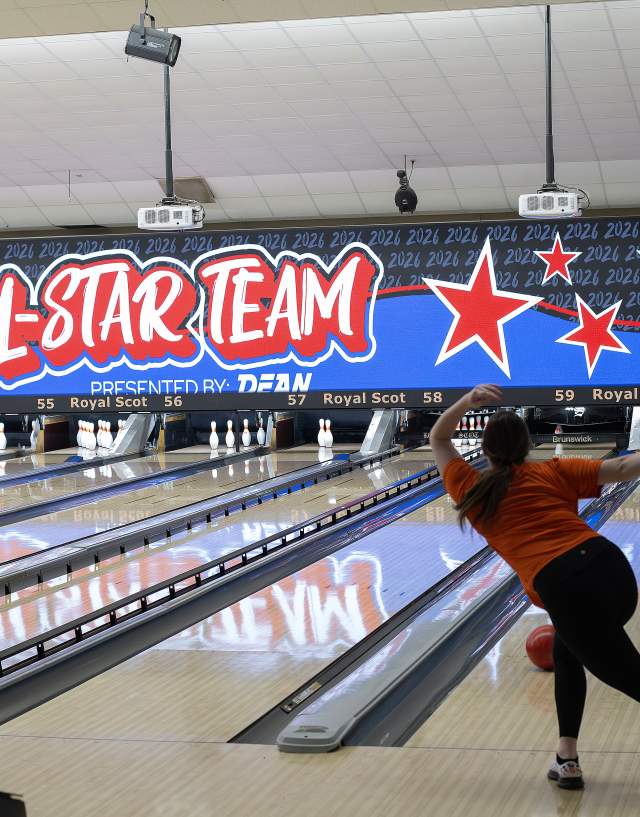Line of bowling lanes with one bowler throwing the ball