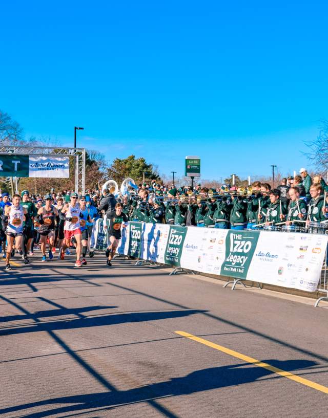 Runners lined up at the start line with crowds surrounding them.