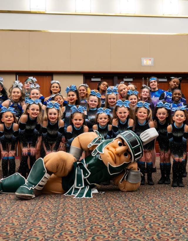 Sparty posing with a group of dancers from the EPIC! Cheer and Dance Championships