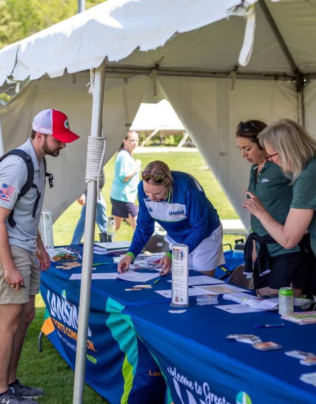 Three volunteers help an individual check in at an event.