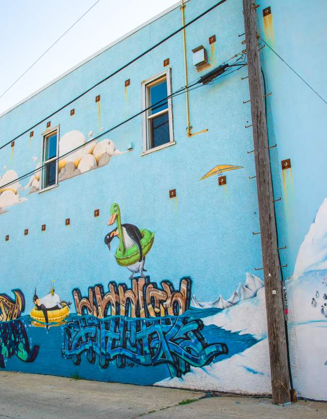 light blue mural featuring penguins on the side of a building