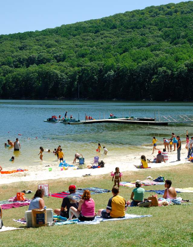 Visitors relax on the beach and enjoy swimming in the lake.