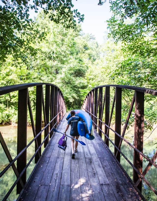 A woman carrying a kayak over a bridge at the Powers Island unit of the Chattahoochee River National Recreation Area.