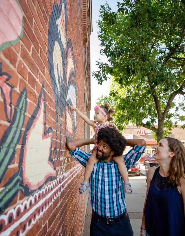 People exploring downtown Stevens Point in the Summertime by the Polish Chicken Mural