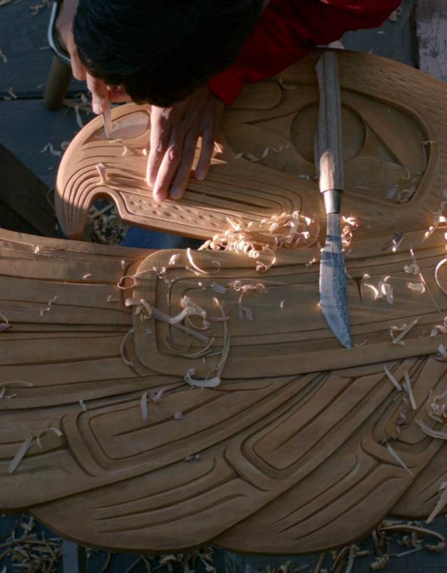 A man uses carving tools to make a work of art.