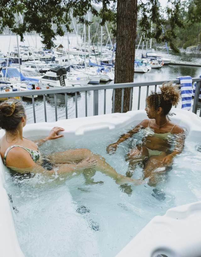 Two women soak in a hot tub overlooking the marina.